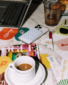 Mesa de trabajo con computadora, café, materiales gráficos y papeles durante una Sesión de Estudio