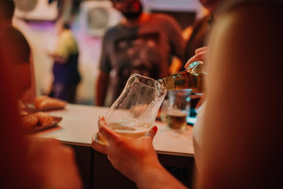 Cerveza servida en un vaso de botella reutilizada en la cantina de Así no más