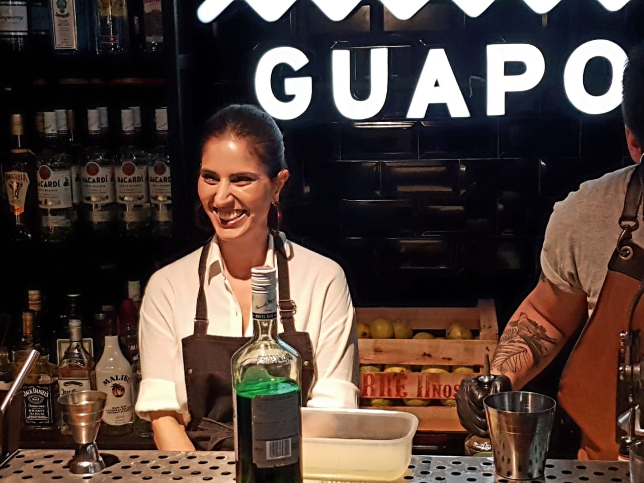 Encuentro gastronómico detrás de la barra, con el cartel luminoso de GUAPO al fondo